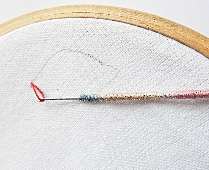 Bring up the loop of thread to the surface of the hoop with the tambour needle