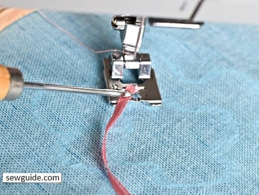 inserting the ribbon trim through the braiding foot.