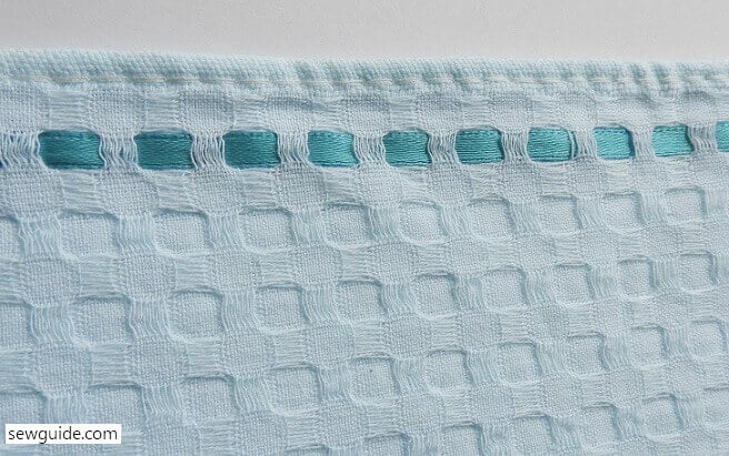 Ribbon woven through the fabric weave in swedish embroidery