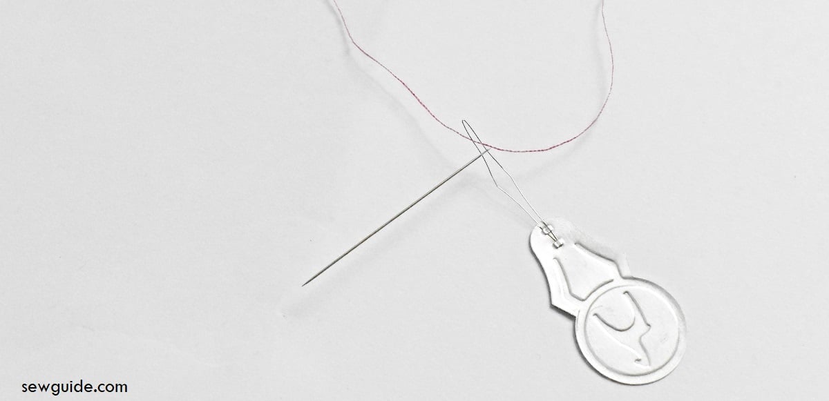 insert the thread through the loop of the threader