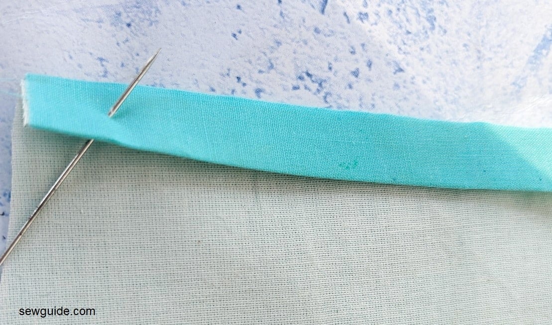 bring up the needle from under the folded fabric