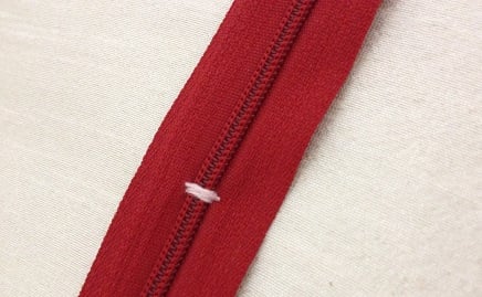 sewing a zipper stop with thread and needle